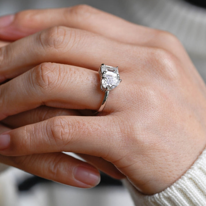 Pear cut engagement ring with emerald side stones